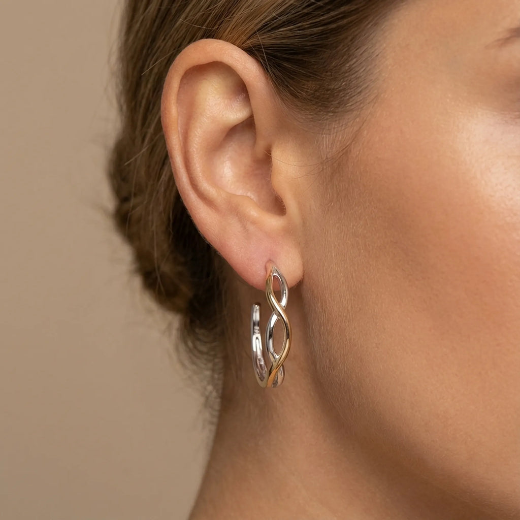 Two-tone silver and gold bypass hoop earring on the ear, side profile — open hoop in 925 sterling silver, Dubai.