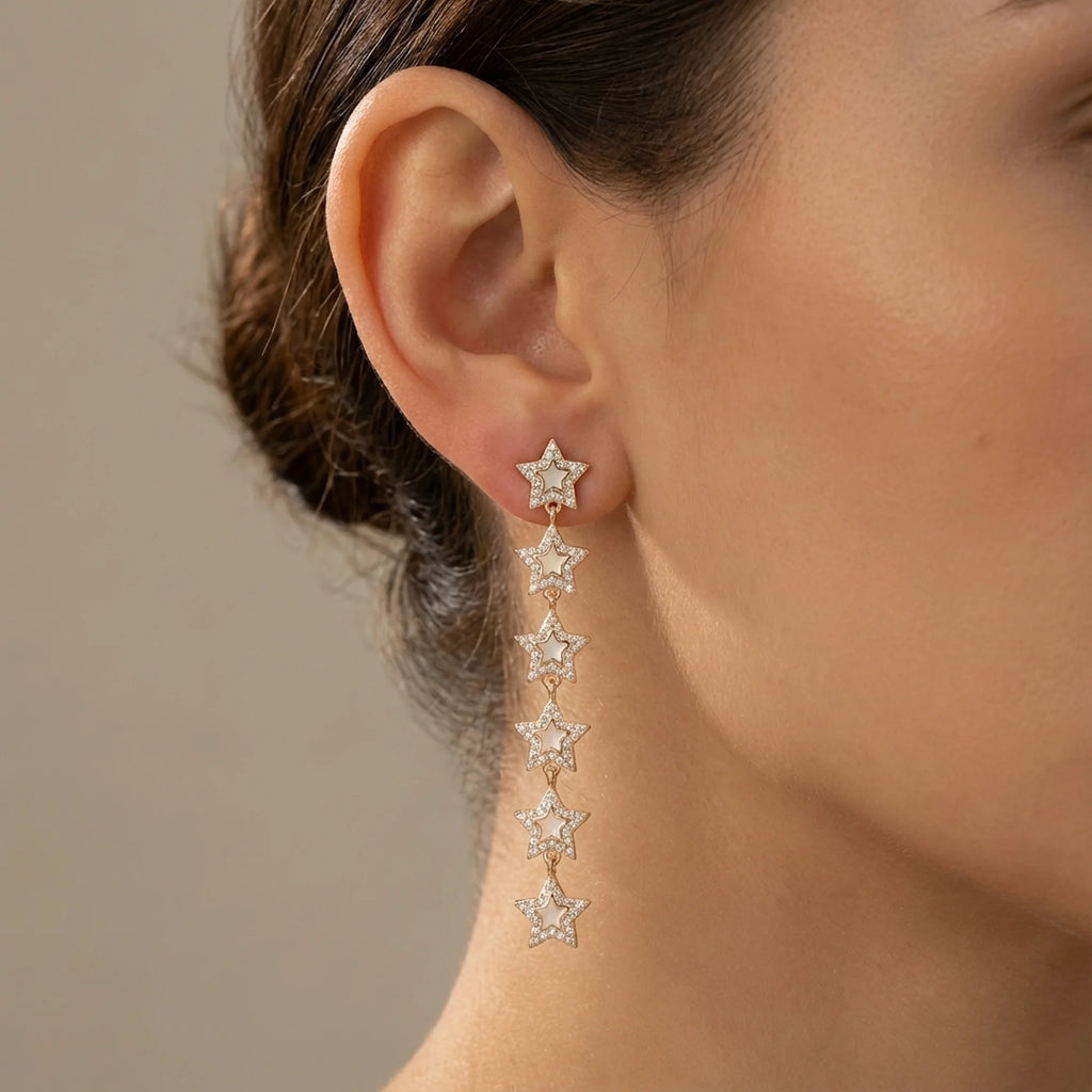Woman wearing 18K gold plated star drop earrings with cubic zirconia outdoors in Dubai.
