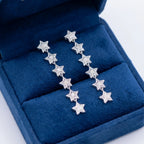 Rhodium plated silver star drop earrings with cubic zirconia presented in a blue jewelry box in Dubai.