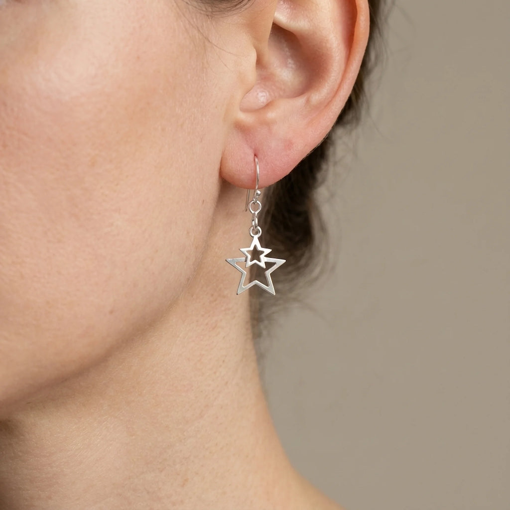 Woman wearing 925 sterling silver nested double star drop earrings against a neutral background indoors in Dubai.