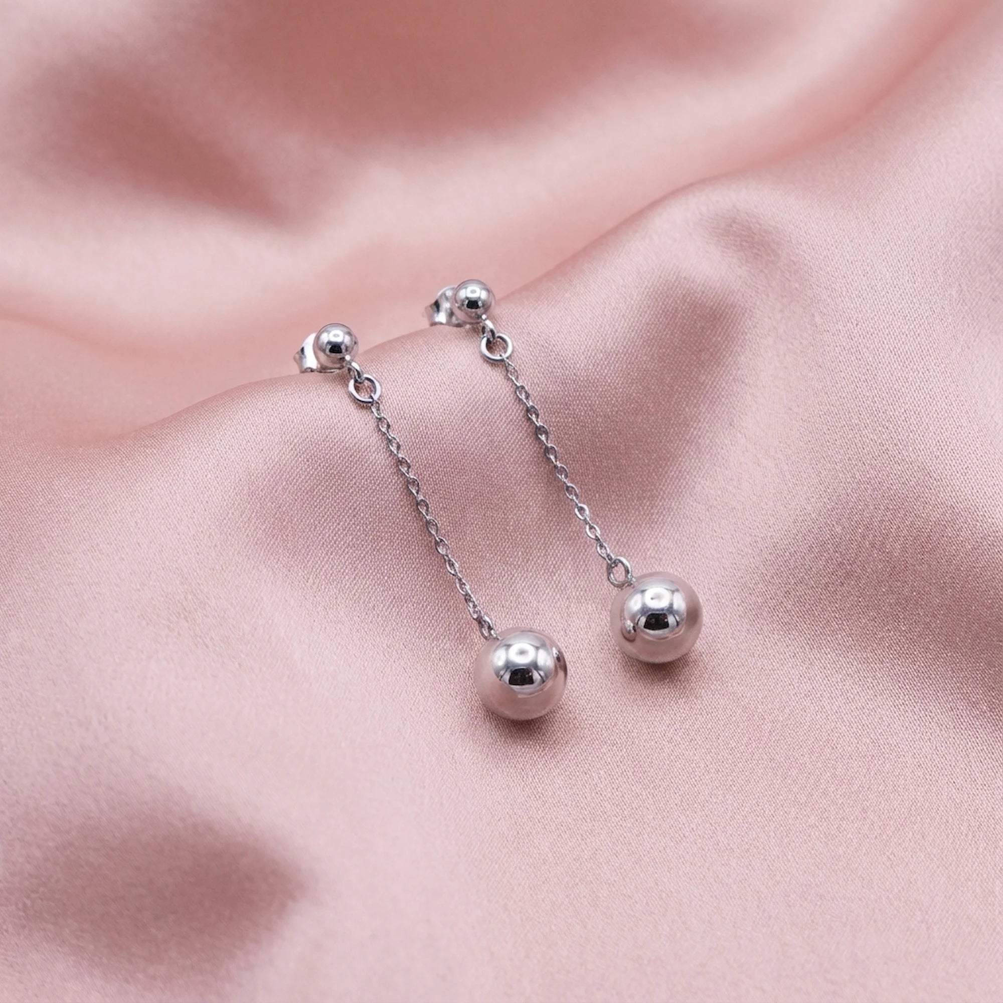 925 sterling silver chain drop earrings with 6mm polished spheres displayed on pink fabric in Dubai.