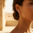 Cherry pavé stud earring worn on ear — warm 18K gold with rose crystals, Dubai heritage architecture background