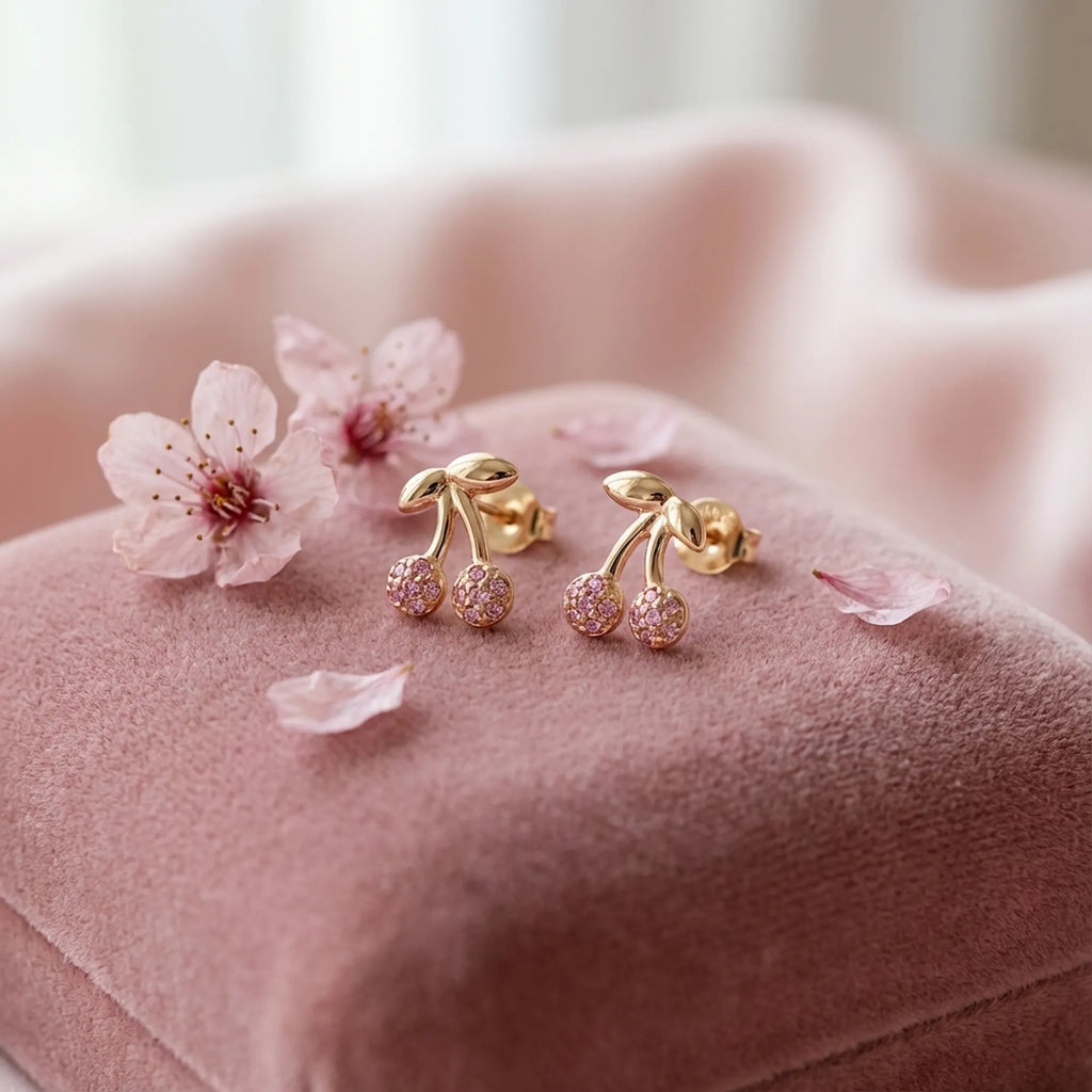 Cherry stud earrings with rose pavé crystals on pink velvet surface with cherry blossom flowers — gifting context