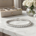 Rhodium-plated classic iced line bracelet displayed on a marble countertop next to a jewelry box and white roses