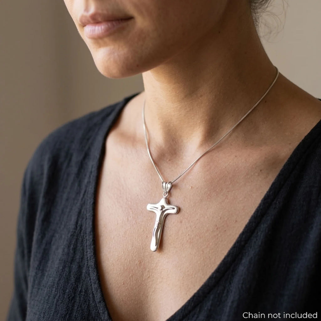 Woman wearing a rounded mirror-polished 925 sterling silver crucifix pendant, chain not included.