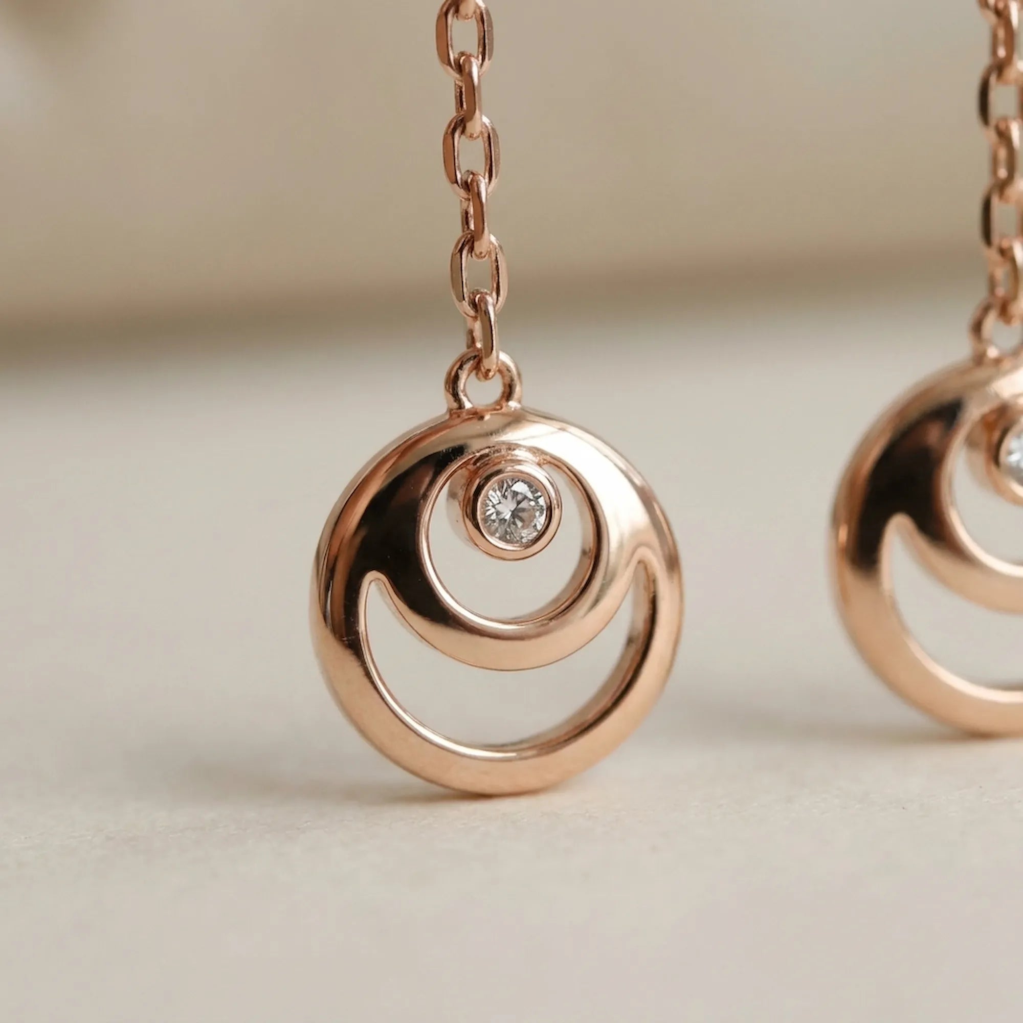Close-up of rose gold crescent moon hilal charm — circular frame with open arc and bezel-set CZ, 18K rose gold 925 silver