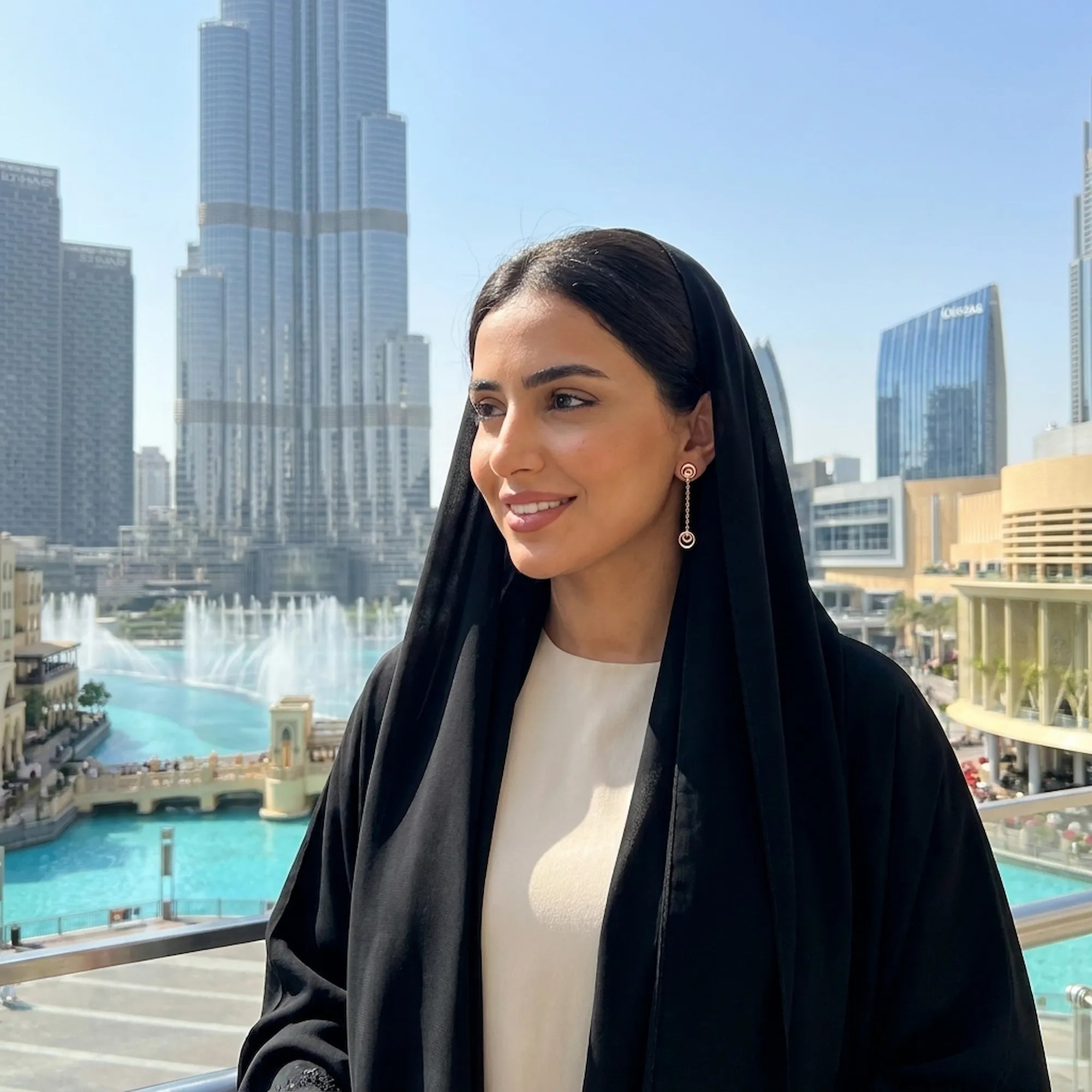 Crescent moon rose gold drop earring worn by model with black abaya — Burj Khalifa and Dubai Fountain in background
