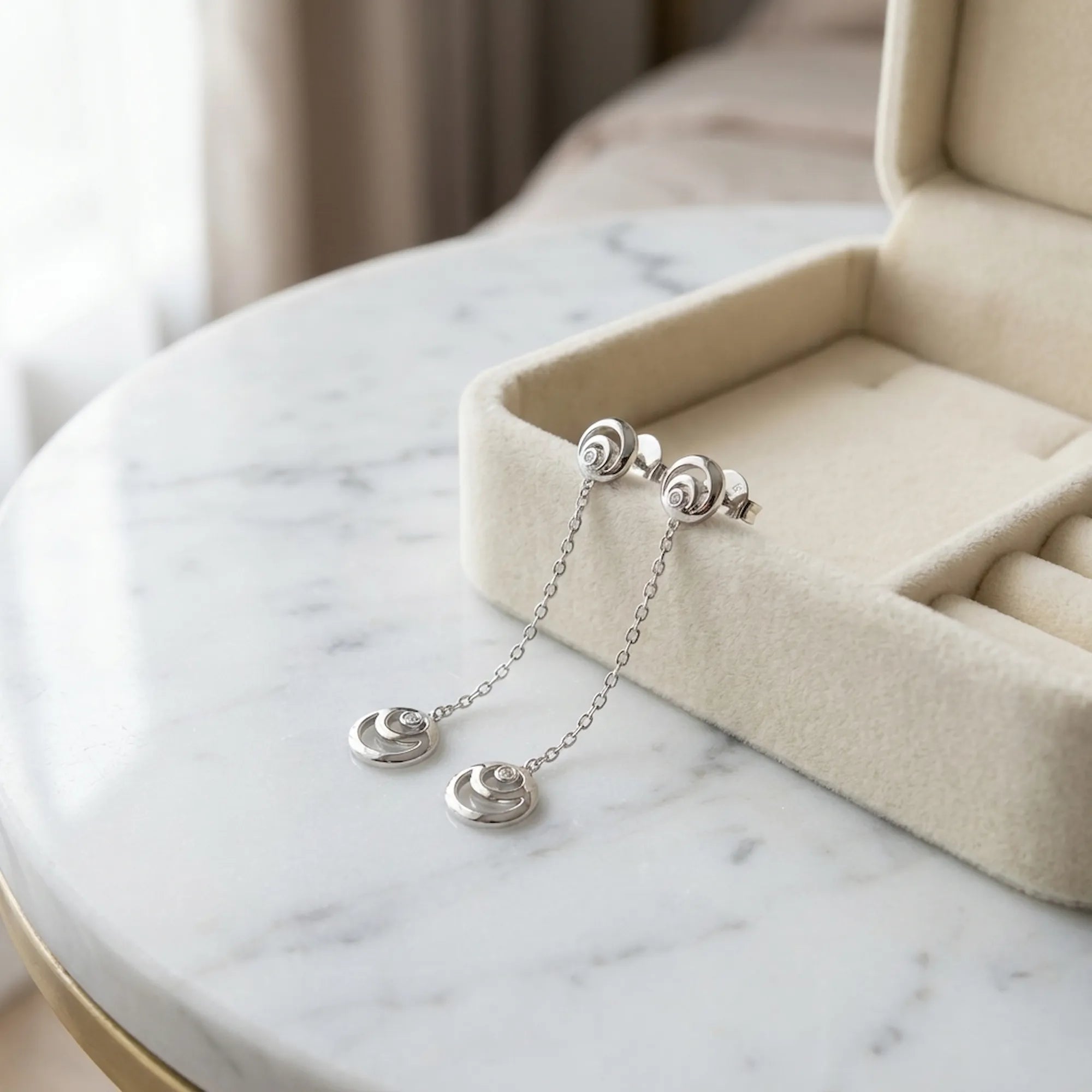 Rhodium silver crescent moon drop earrings beside open cream velvet gift box on marble — 925 sterling silver gifting