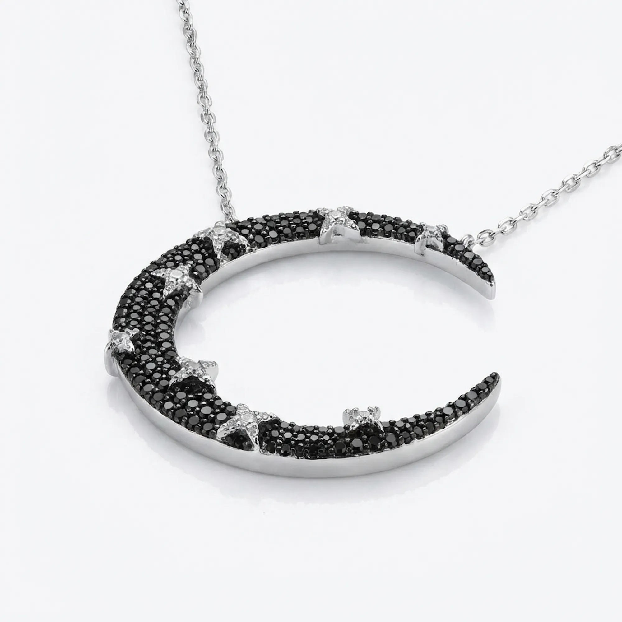 Angled view of 925 silver crescent moon pendant — full black zircon pavé with white CZ star detailing, neutral background
