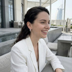 Woman wearing 925 silver crescent moon hoop earrings outdoors near the Burj Al Arab in Dubai.