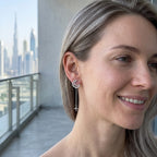 Woman wearing rhodium silver crescent moon star drop earrings with cubic zirconia, Burj Khalifa Dubai in background.