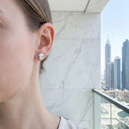 Round dome stud earring on model's ear with Dubai skyline skyscrapers in background — 925 sterling silver