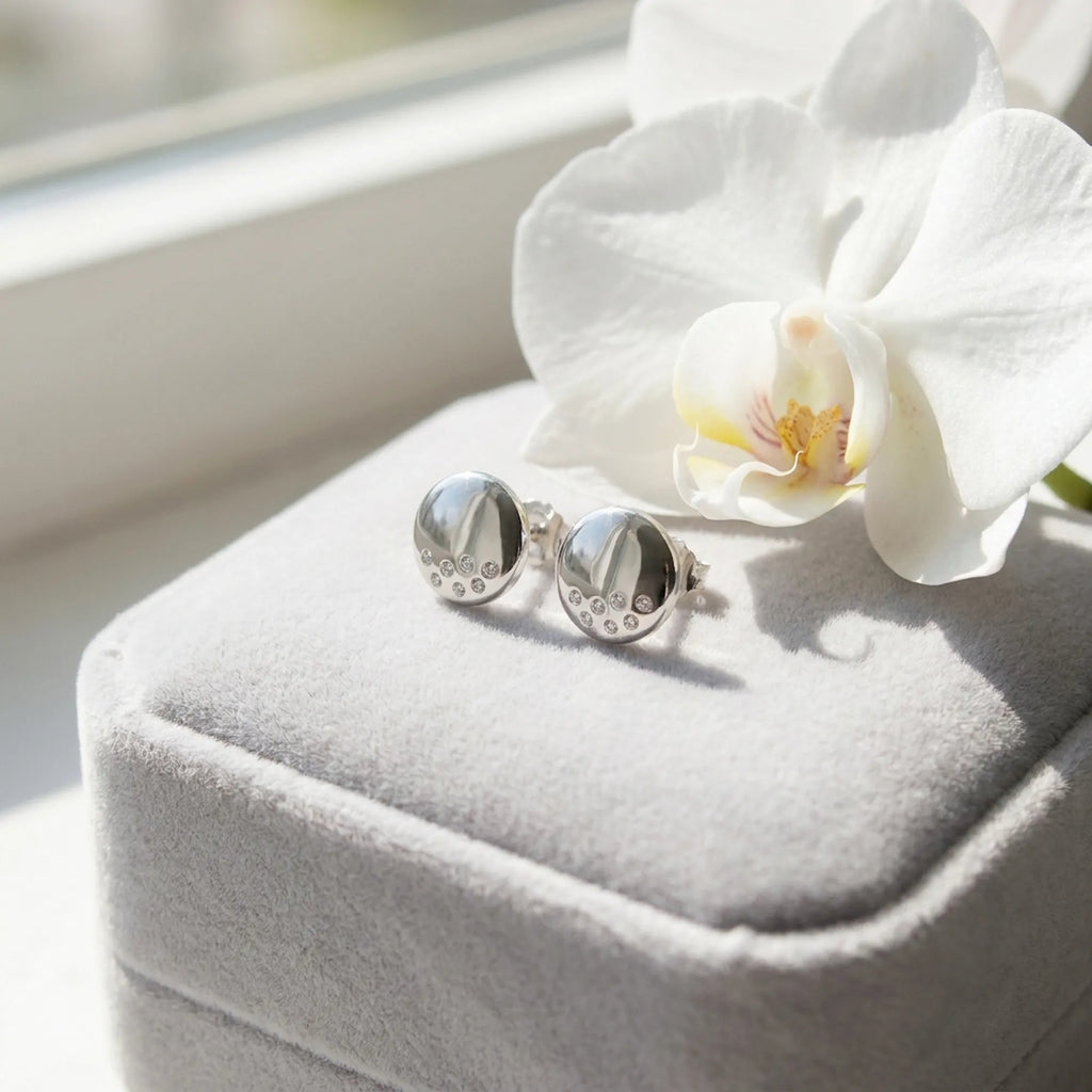 Silver dome stud earrings on grey velvet gift box with white orchid flower — gifting presentation