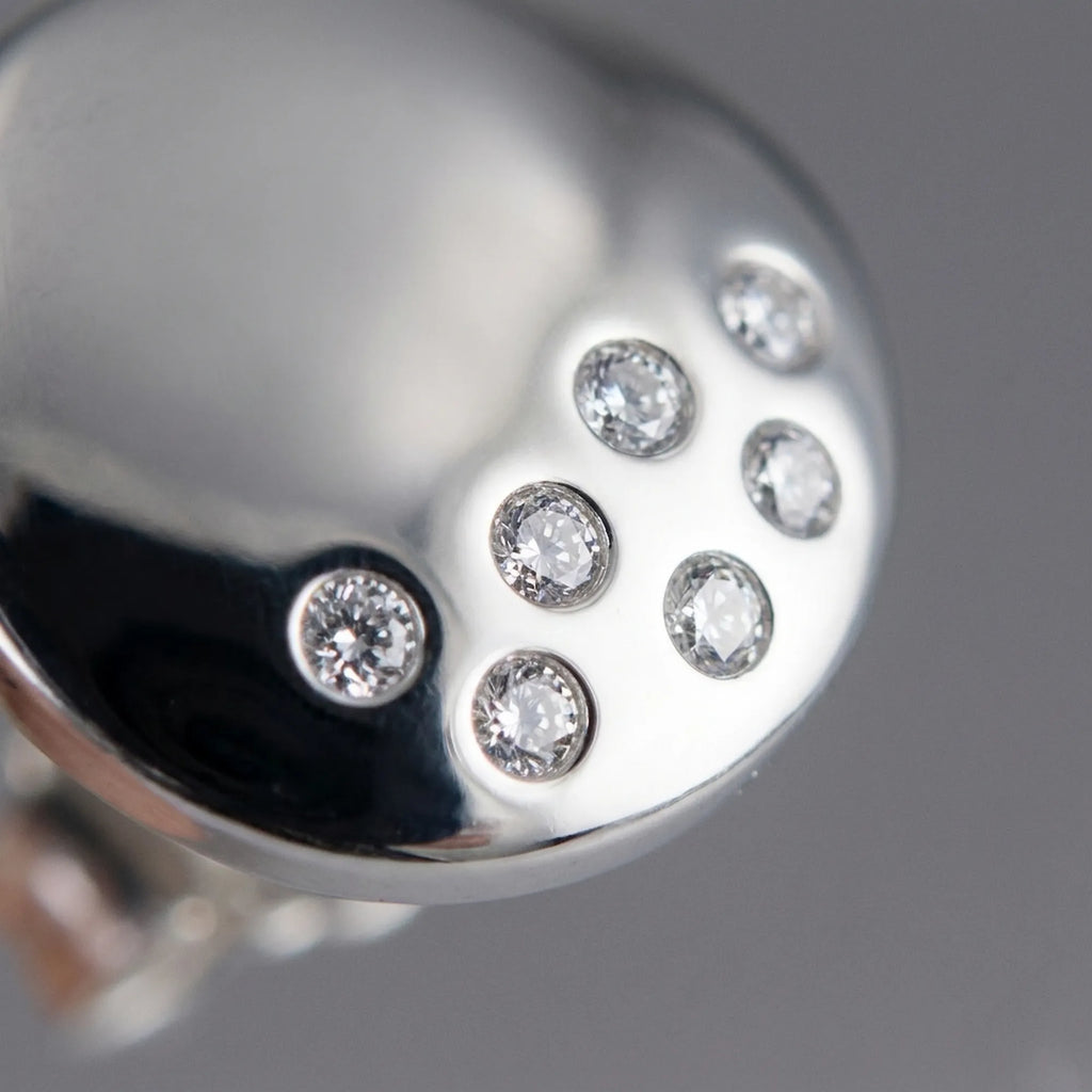 Close-up of seven individually bezel-set CZ stones in constellation scatter on high-polish 925 silver dome stud earring