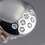 Close-up of seven individually bezel-set CZ stones in constellation scatter on high-polish 925 silver dome stud earring