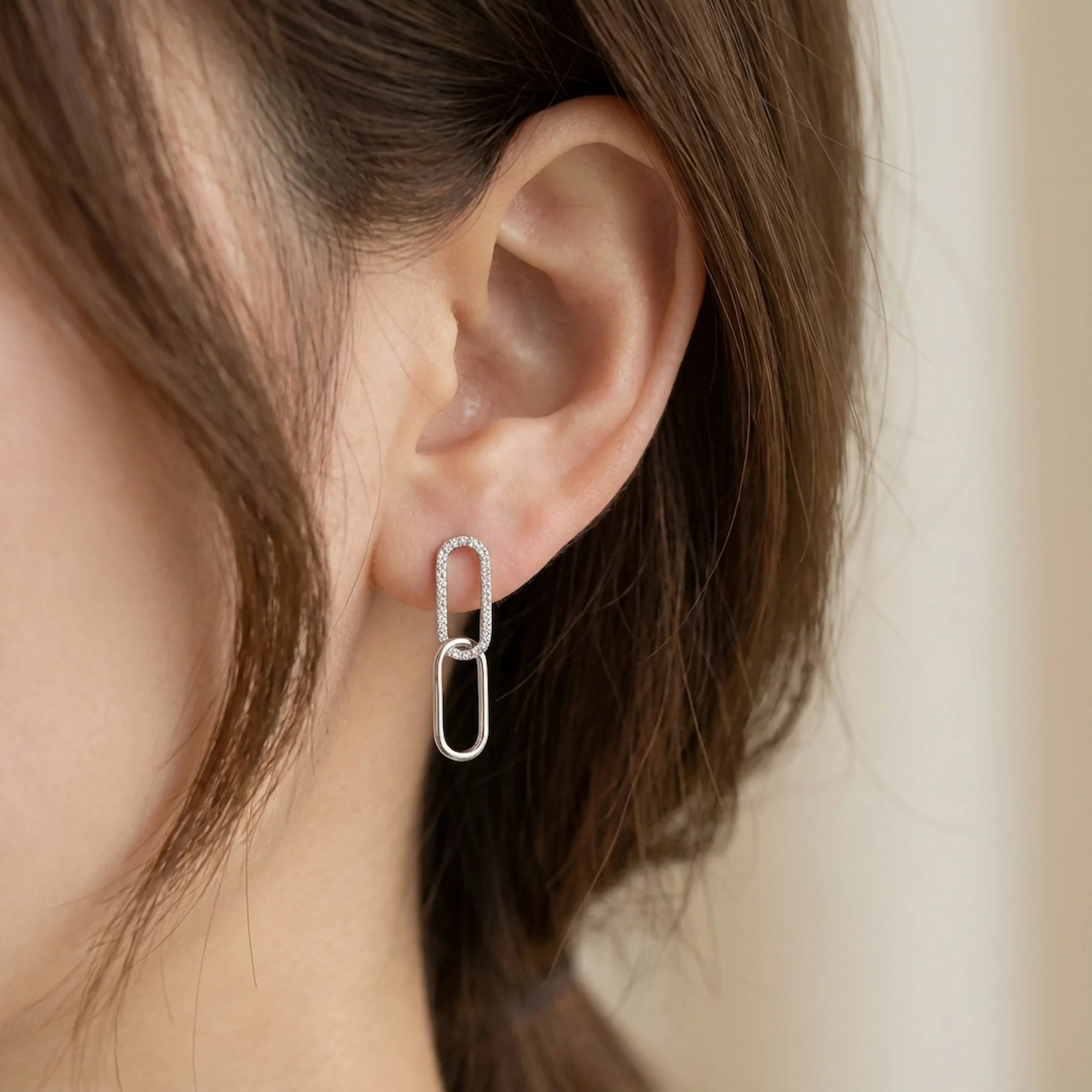 Woman in Dubai wearing double link silver drop earrings with clear stones on the top loop.
