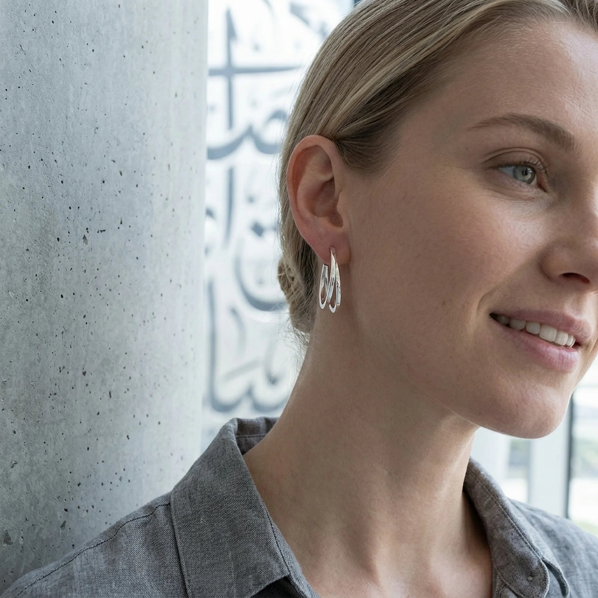 Woman wearing 925 sterling silver split hoop earrings with double-row with blurred future museum calligraphy in Dubai.