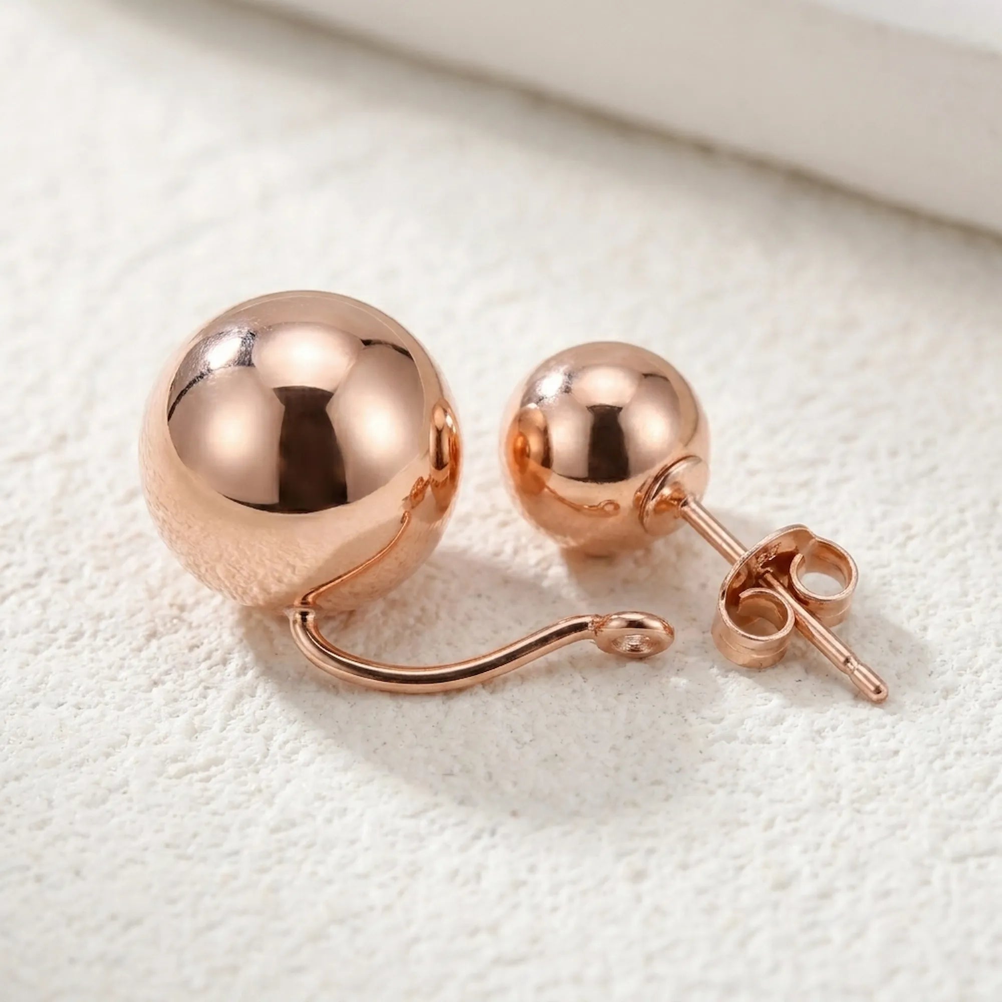 Double sphere earring components separated on white — large and small rose gold 925 silver balls, connector hook visible