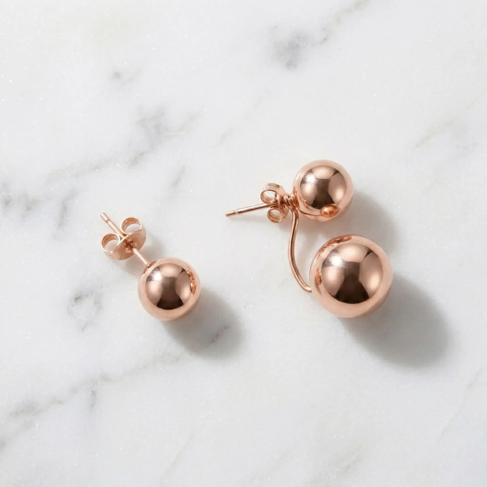Both earring configurations on marble — stud-only left and full 2-in-1 right, rose gold 925 silver