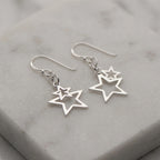 Nested double star drop earrings in 925 sterling silver with pure-silver plate resting on marble, available in Dubai.