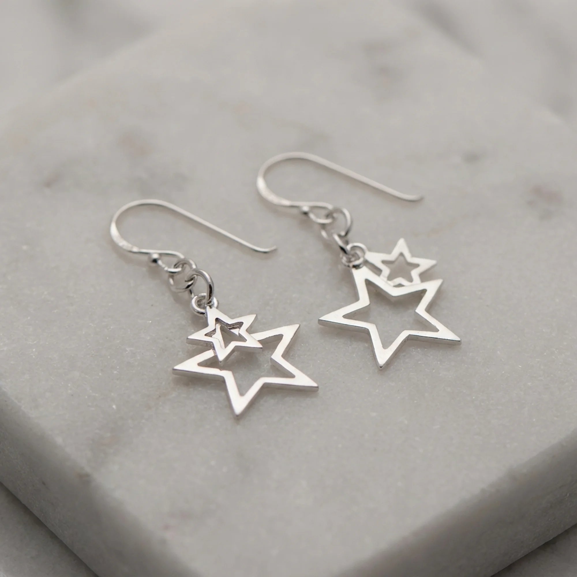 Nested double star drop earrings in 925 sterling silver with pure-silver plate resting on marble, available in Dubai.