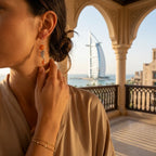 Stylish woman in Dubai wearing our bohemian 925 sterling silver leaf chain drop earrings with matte peach stones at golden hour.