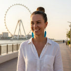 Model wearing electric blue feather drop earrings at Bluewaters Island Dubai — Ain Dubai waterfront, shoulder-grazing dangle