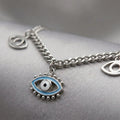 Baby blue enamel evil eye charm necklace variant close-up on grey satin showing centre charm detail