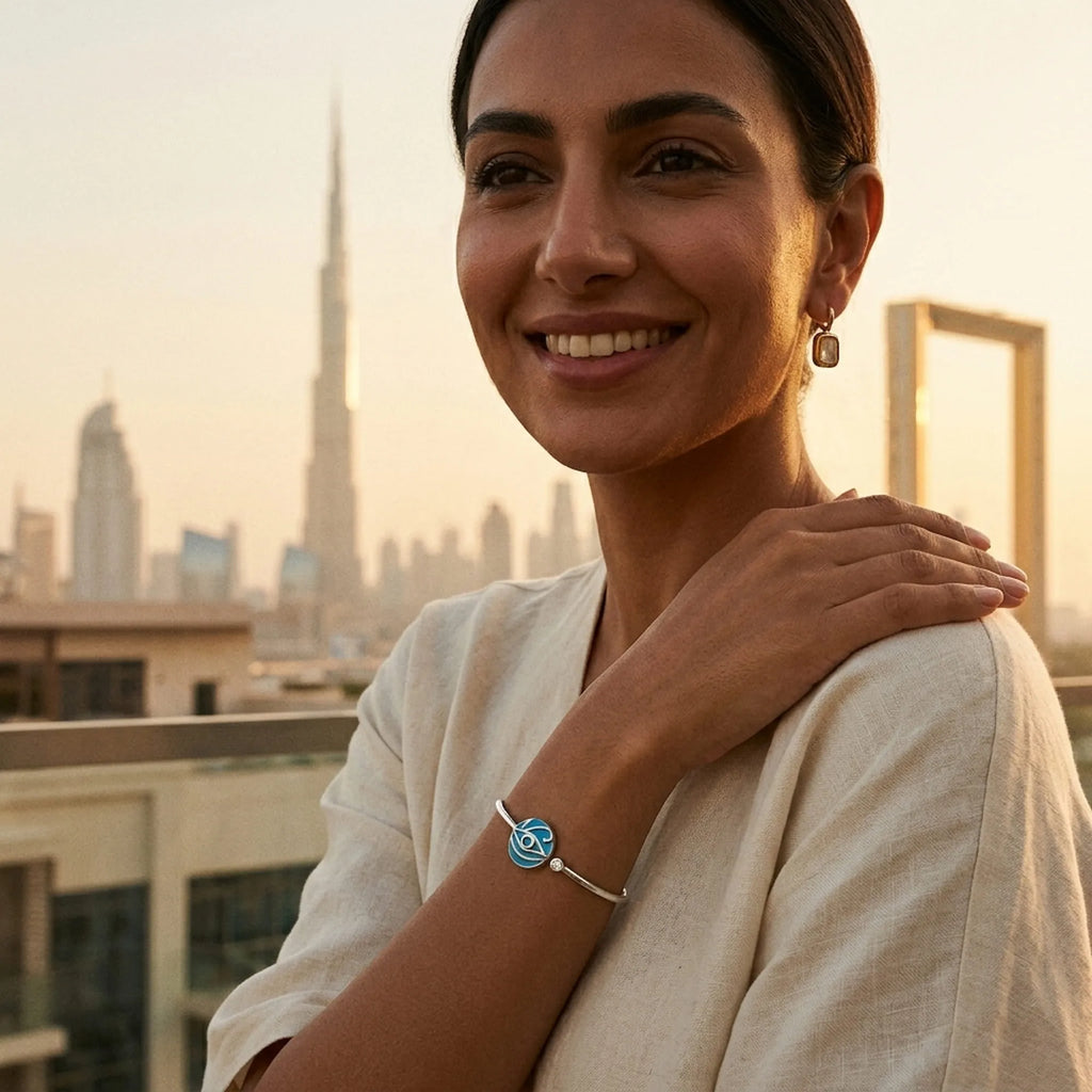 Woman wearing azure blue topaz evil eye cuff bangle, Burj Khalifa and Dubai Frame skyline behind her