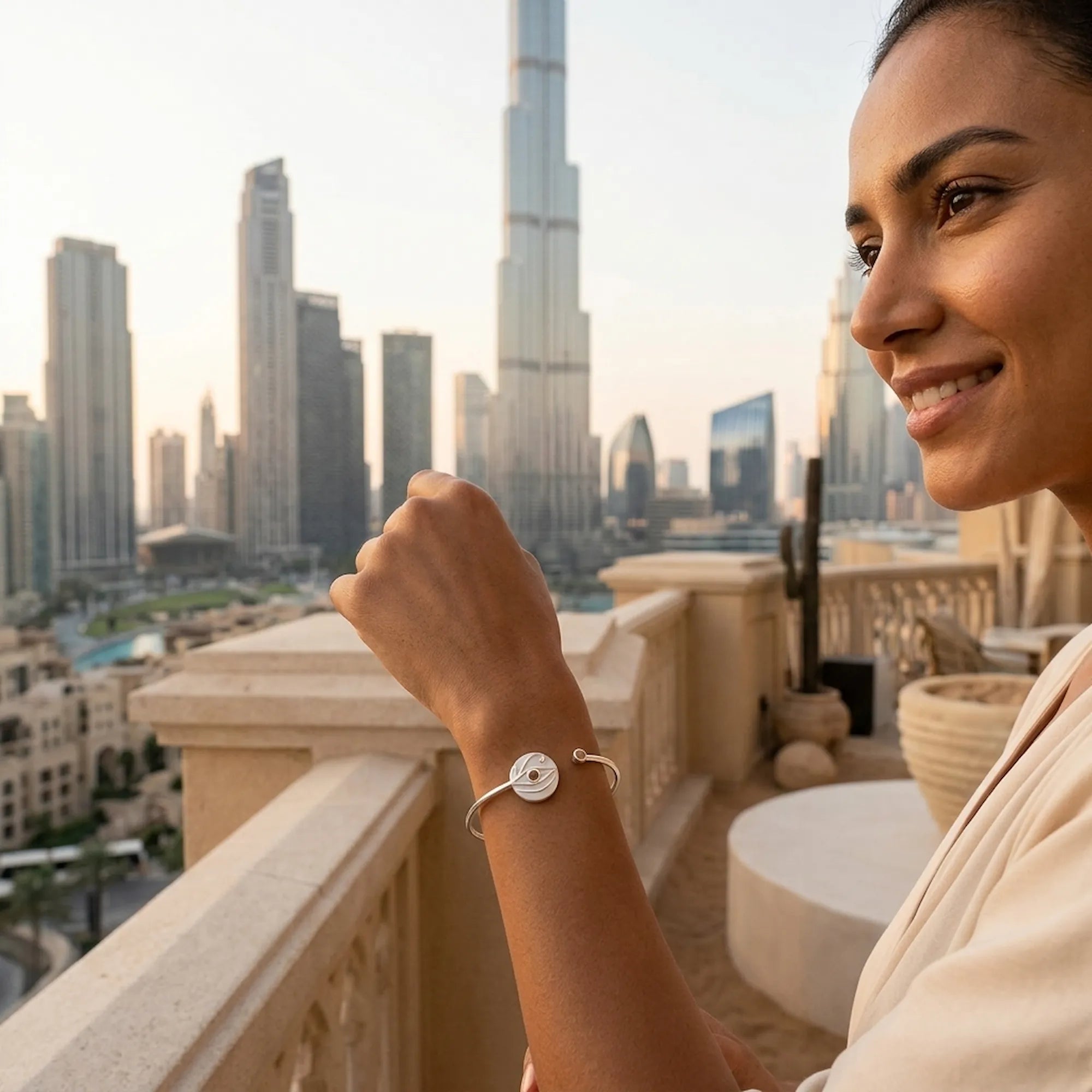 Woman wearing white dual opal evil eye cuff bangle on rooftop, Burj Khalifa in background, Dubai