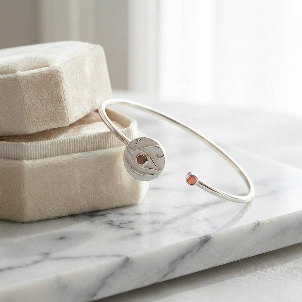 White dual opal evil eye cuff bangle on cream jewellery box, white marble, warm studio lighting