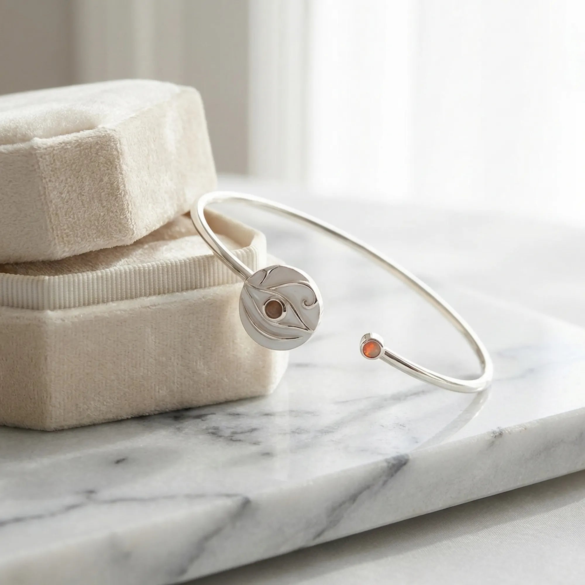 White dual opal evil eye cuff bangle on cream jewellery box, white marble, warm studio lighting