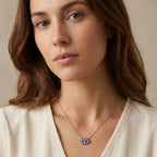 Royal blue enamel evil eye pendant necklace worn at upper chest on 925 silver cable chain, warm neutral background