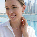 Model wearing 70 mm CZ silver hoops with a Dubai Marina high-rise backdrop.
