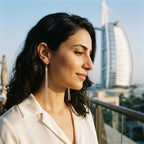 Woman wearing extra long 925 silver tassel dangle earrings with the Burj Al Arab in Dubai.