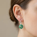 Silver French hook drop earring with green eye motif worn on model