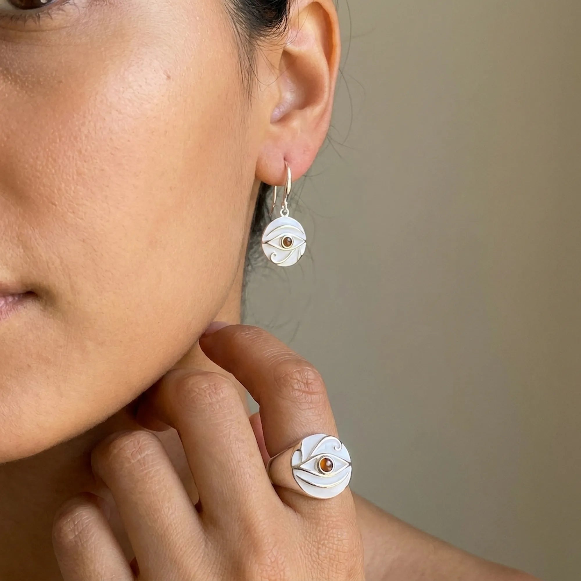 Woman wearing white enamel and fire opal signet ring with matching drop earrings
