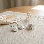 Minimalist white on white jewelry set resting gracefully on linen fabric