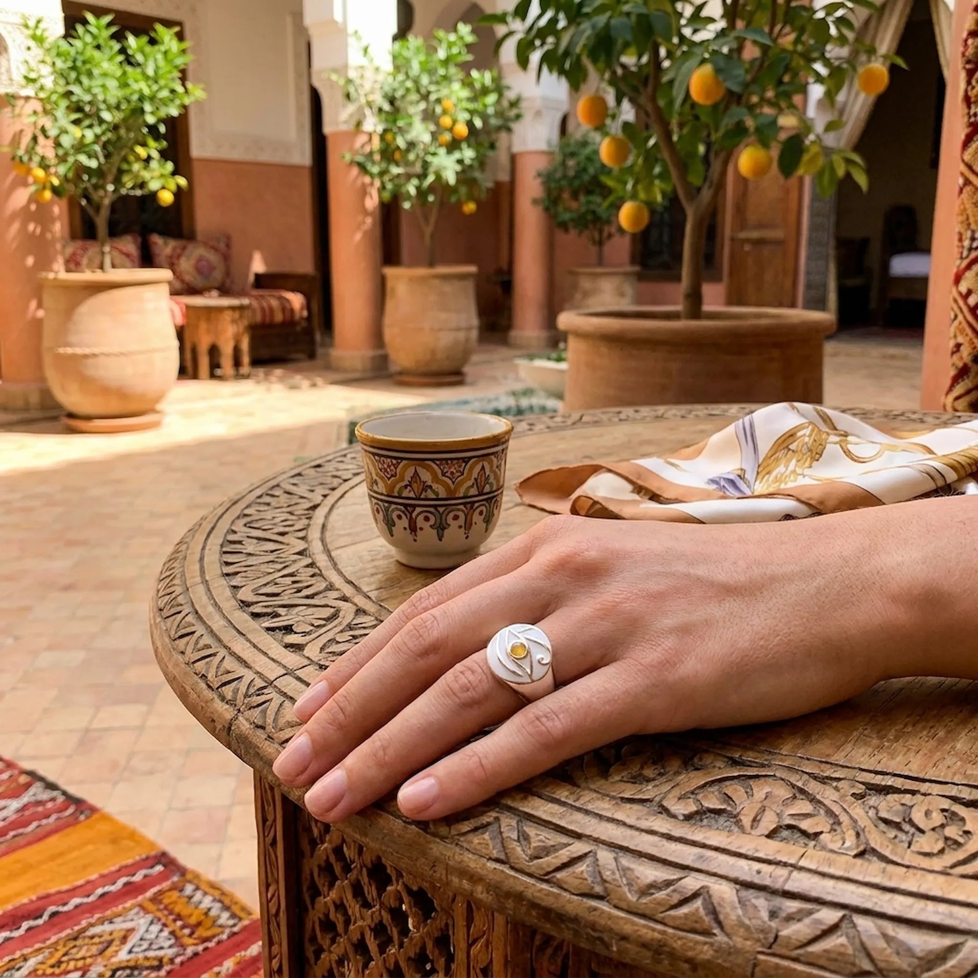 Eye of Horus white enamel ring with yellow opal iris on carved wooden table, traditional courtyard, Dubai