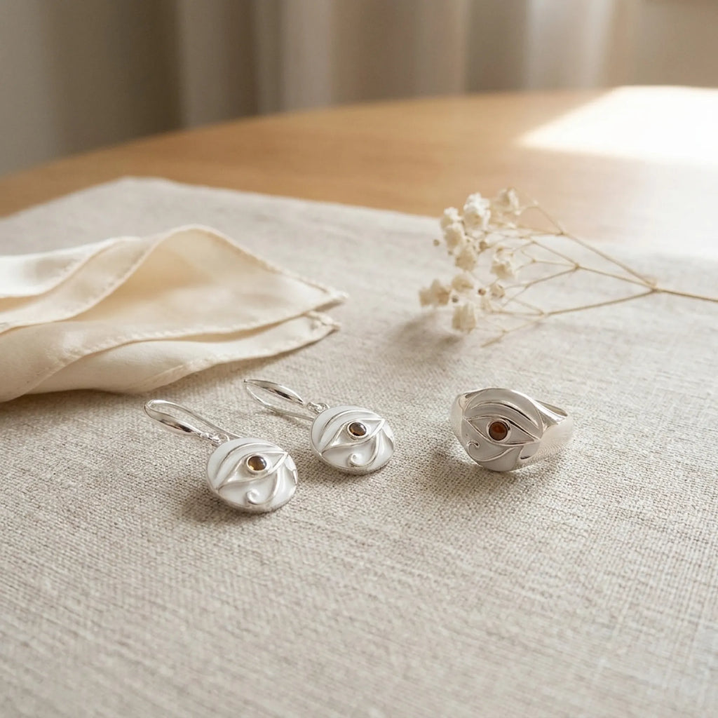Eye of Horus yellow opal ring and earrings flat lay with Luna Dura dust pouch on cream linen