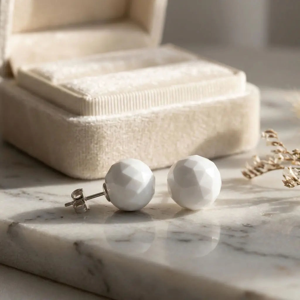 Geometric faceted white resin stud earrings highlighting reflective multi-angled cuts and polished 925 silver posts.