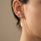 Woman wearing 18K gold plated sterling silver falling leaves drop earrings with cubic zirconia, styled in Dubai.
