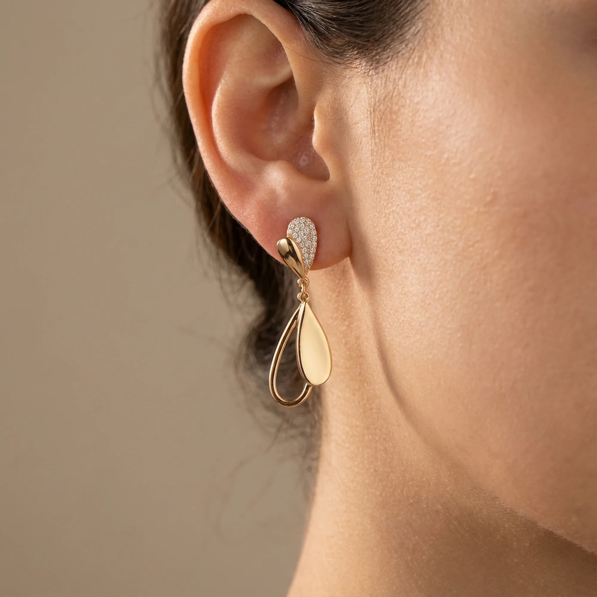 Woman wearing 18K gold plated sterling silver falling leaves drop earrings with cubic zirconia, styled in Dubai.