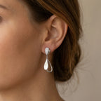 Woman wearing rhodium plated sterling silver falling leaves drop earrings with cubic zirconia, styled in Dubai.