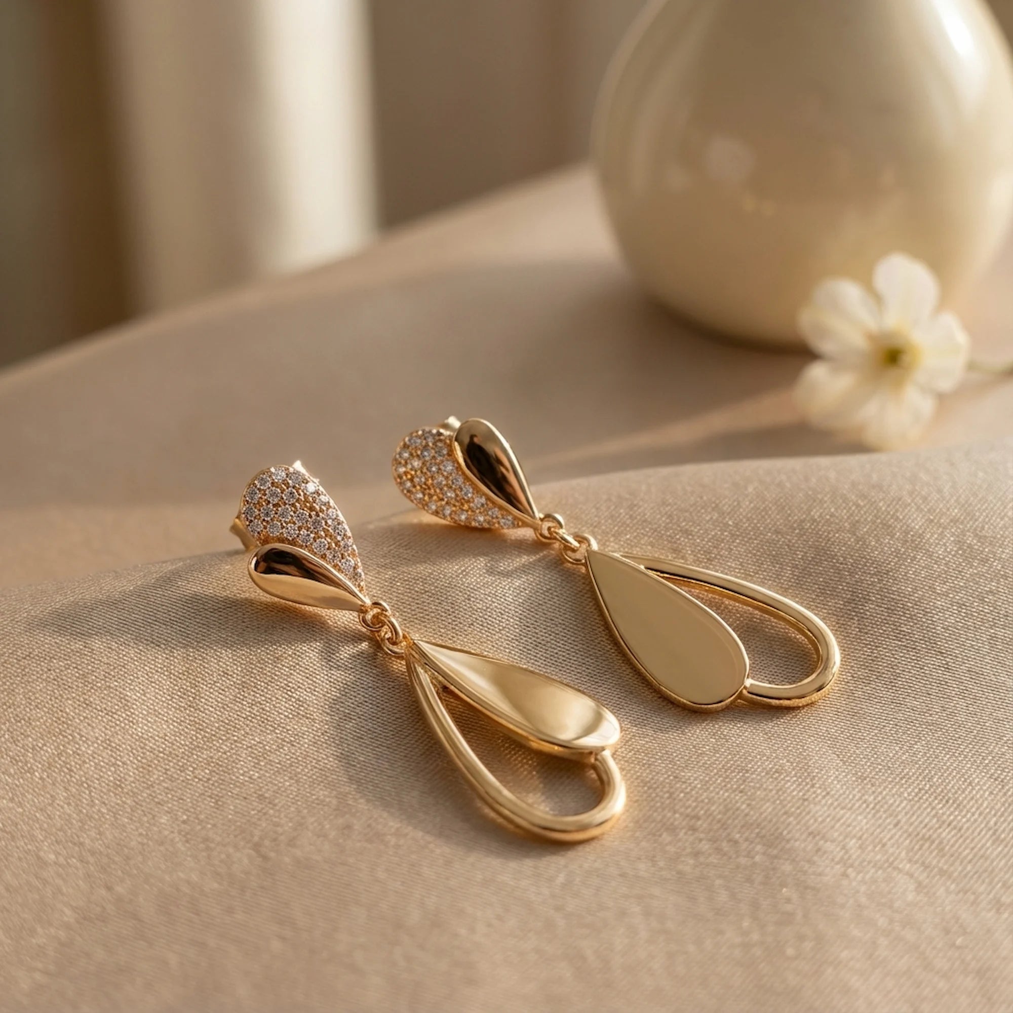 18K gold plated sterling silver falling leaves drop earrings with cubic zirconia resting on silk fabric in Dubai.
