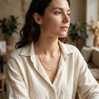Woman wearing a fine silver paperclip-link necklace with an open-collar cream shirt.
