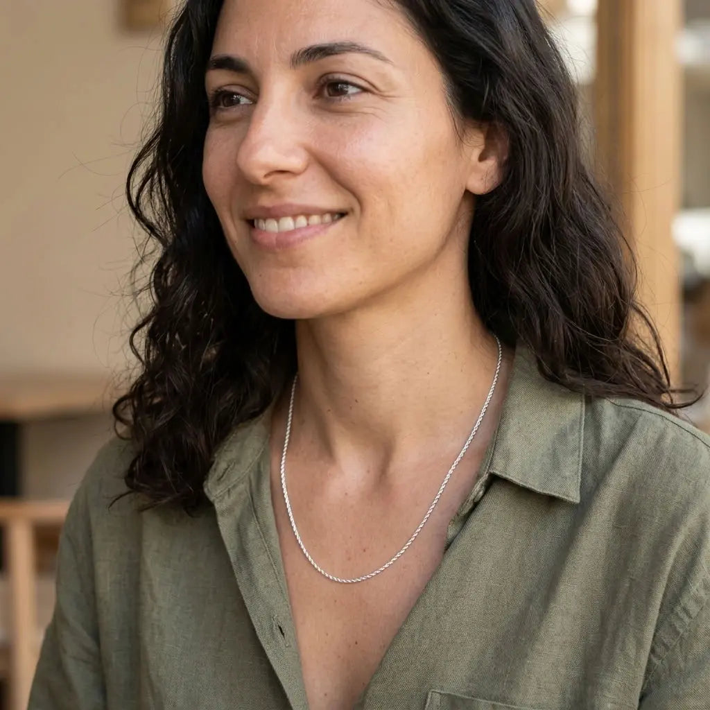 Woman wearing a fine silver-tone twisted chain necklace with an olive-green collared shirt.