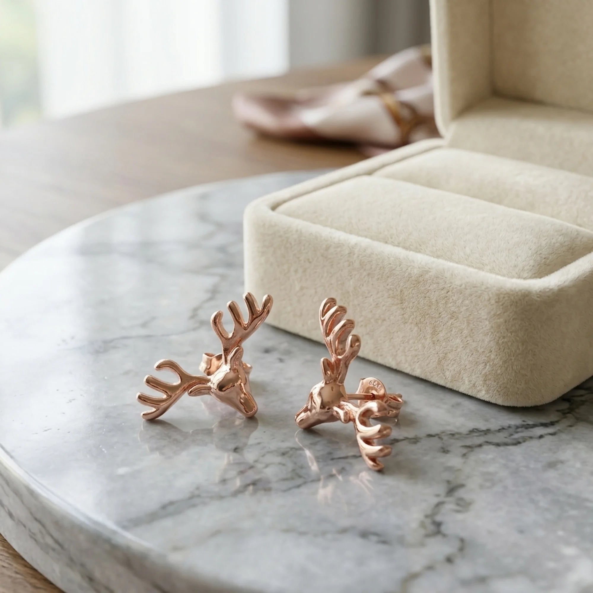 18K rose gold plated 925 sterling silver antler stud earrings displayed on a marble surface in Dubai.