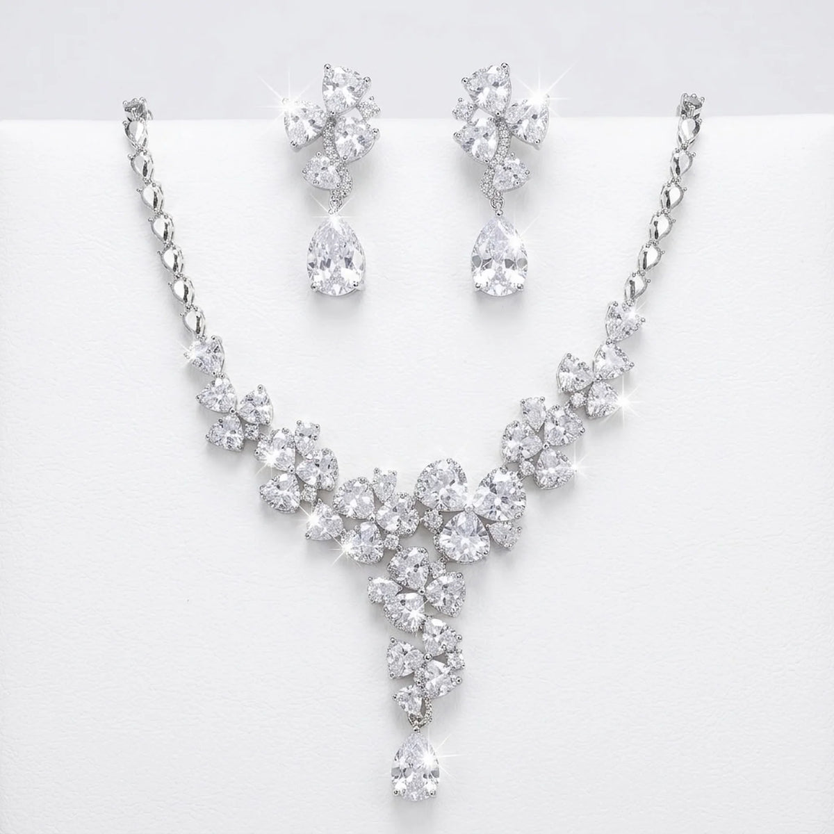 Floral cluster Y-drop necklace and earring set in rhodium-plated cubic zirconia, displayed on a white stand in Dubai.