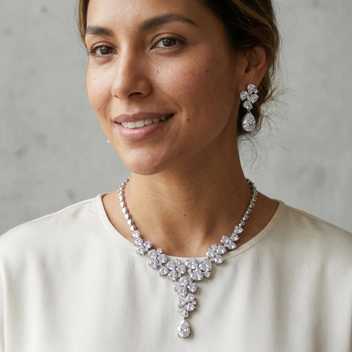 Woman wearing a bridal floral cluster Y-drop necklace and matching cubic zirconia earrings indoors in Dubai.